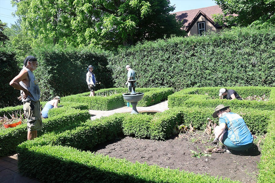 An English-style garden with several people planting things in it